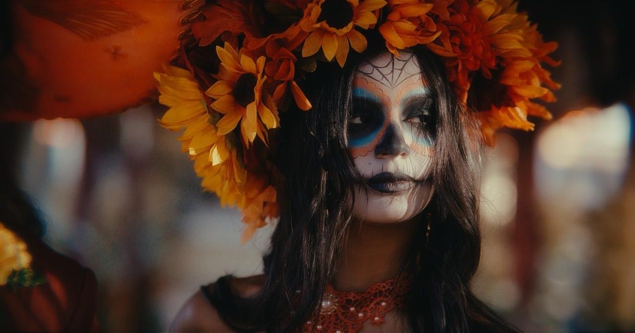 A woman in sugar-skull makeup and a sunflower crown
